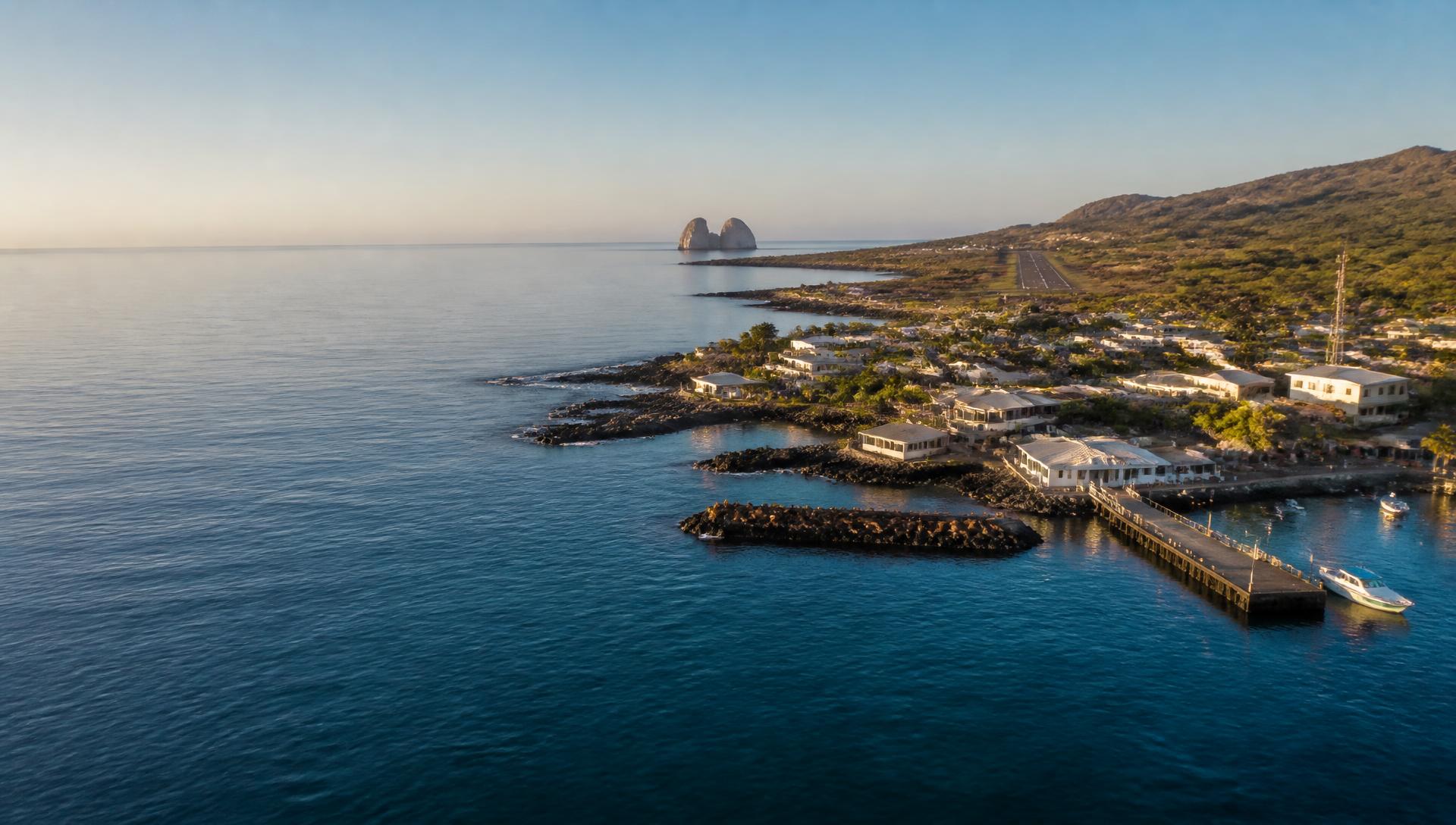 מבט אווירי על San Cristóbal: מזח Puerto Baquerizo Moreno וסירות בחוף, מסלול שדה התעופה מעל העיר ו-León Dormido ברקע הים